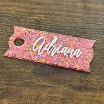 Pink glitter acrylic Stanley cup topper name plate personalized Adriana in white script, on wood