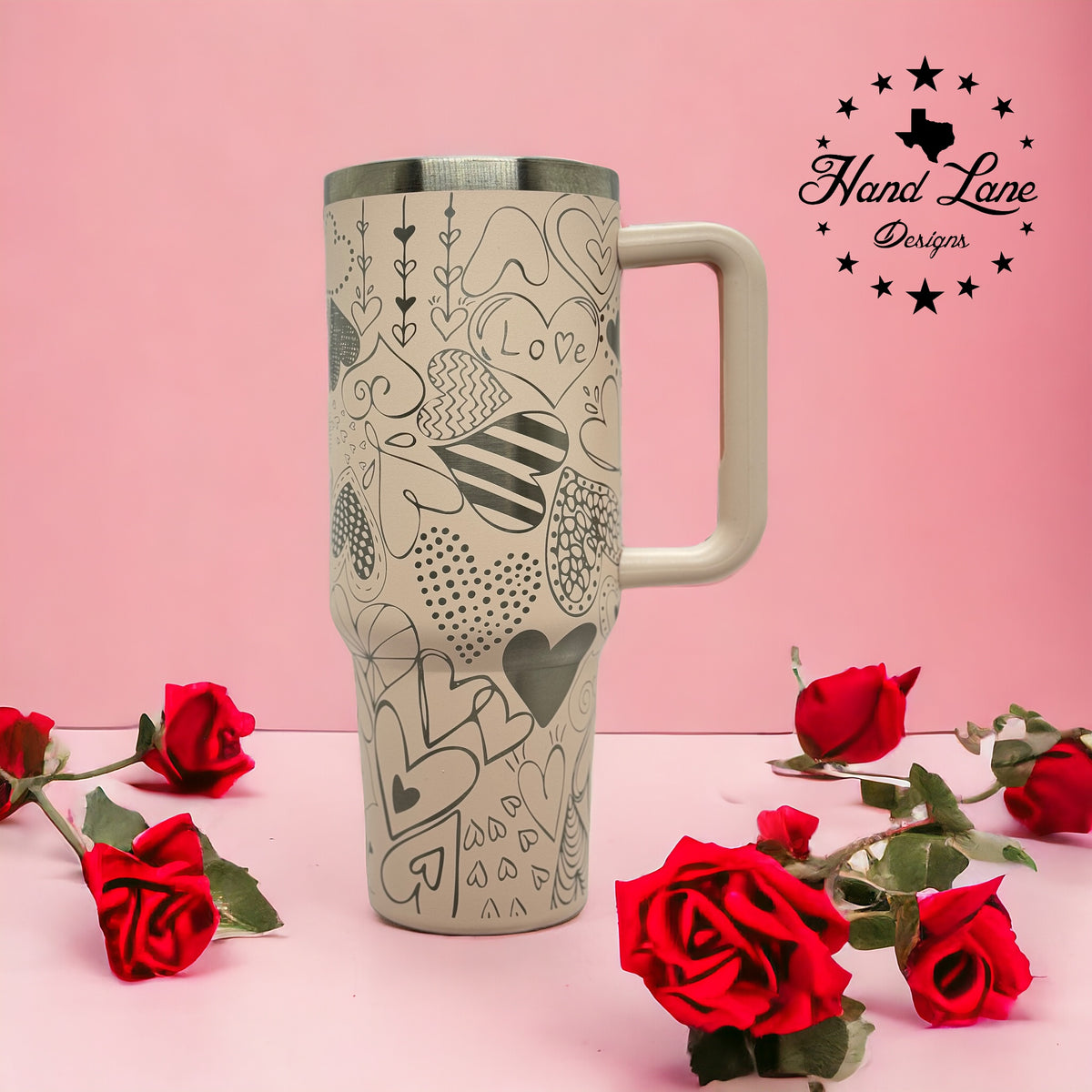 Tan 40oz handled tumbler with laser engraved Valentine heart doodle full wrap, styled with red roses