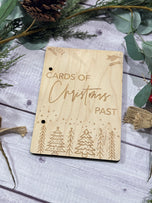 Angled view of wooden Christmas card keeper binder styled with pinecones and holiday greenery