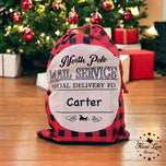 Red buffalo plaid XL Santa sack with North Pole Mail Service design personalized for Carter under a Christmas tree