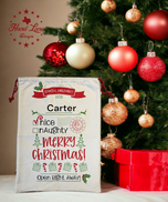 Cream canvas Santa sack personalized Carter with nice and naughty checkboxes and Merry Christmas design beside the tree