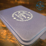 Navy blue cake pan lid engraved with Made with Love and Butter laurel wreath design, angled detail