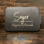 Close-up of black cake pan lid engraving reading Sager, Happiness is Homemade with heart accent