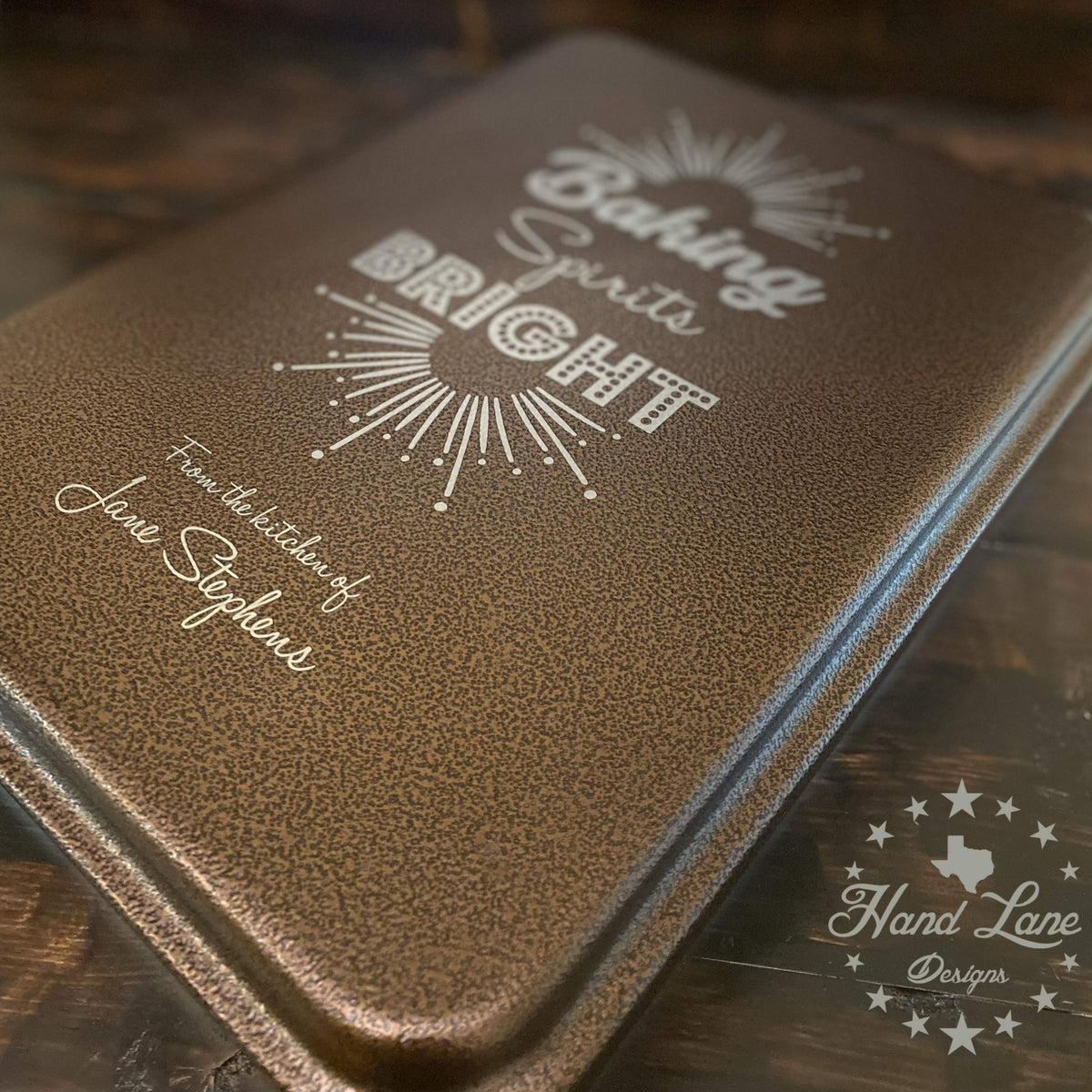 Copper 13x9 cake pan lid engraved Baking Spirits Bright with starburst and From the Kitchen of name, angled view