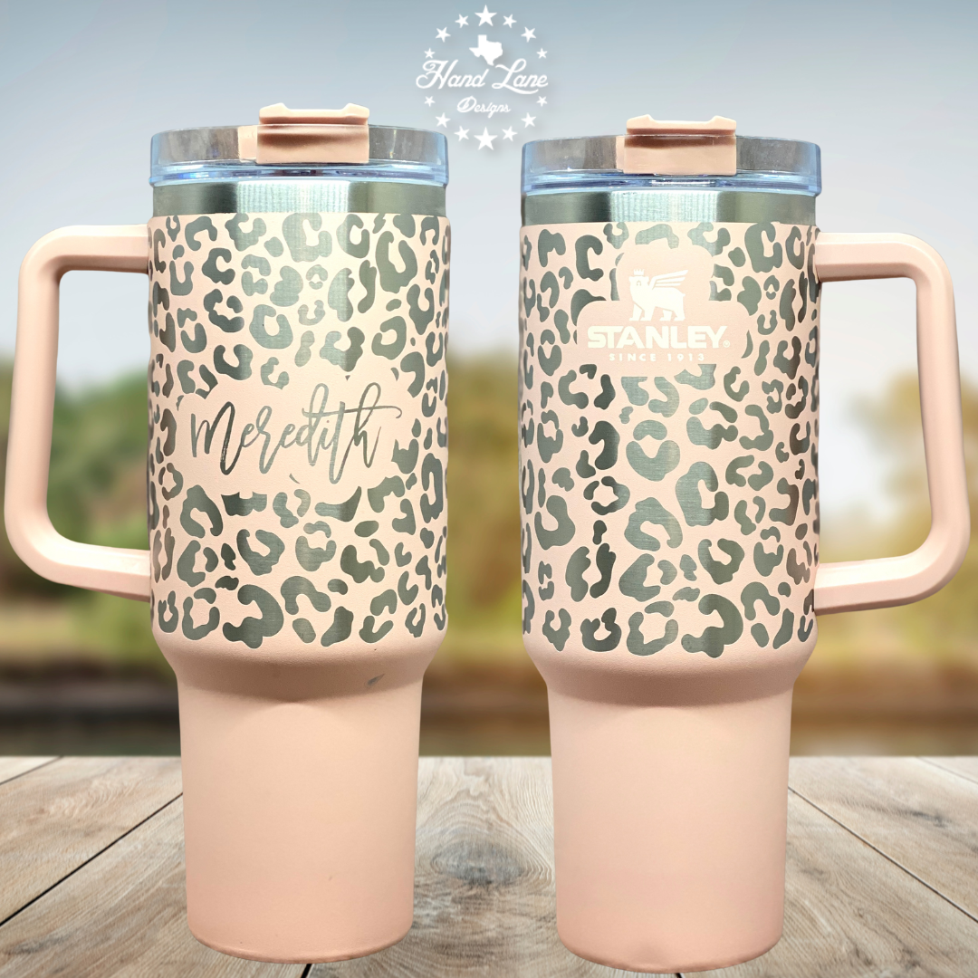 Two peach 40oz Stanley Quencher tumblers with laser engraved leopard print, one personalized with the name Meredith