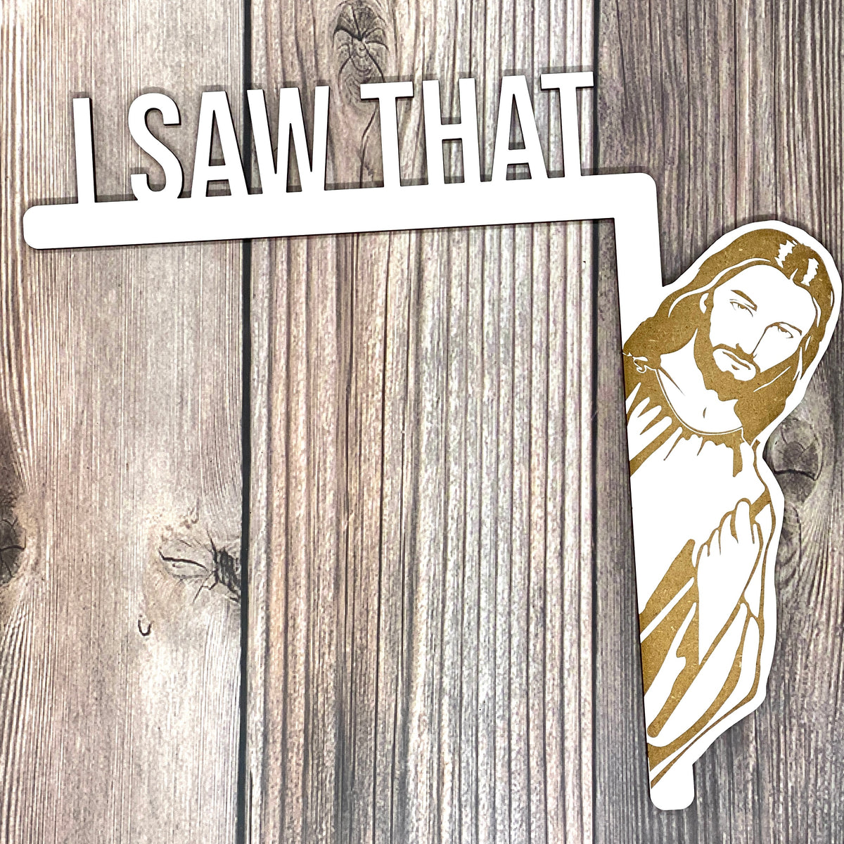 White I Saw That door hanger with laser engraved peeking Jesus on wood, shown on dark planks
