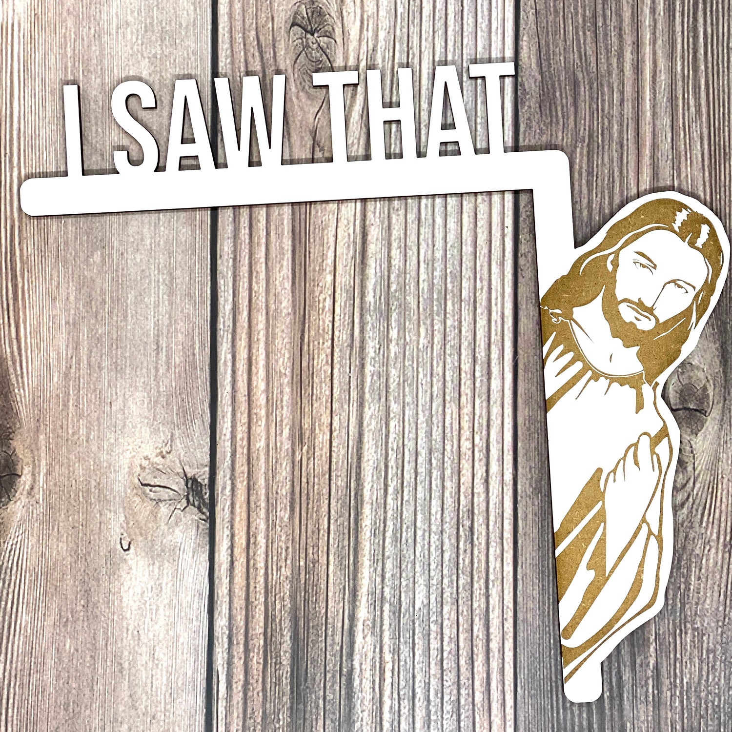 White I Saw That door hanger with laser engraved peeking Jesus on wood, shown on dark planks