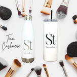 Engraved white Seint Team Cashmere water bottle and skinny tumbler surrounded by makeup brushes
